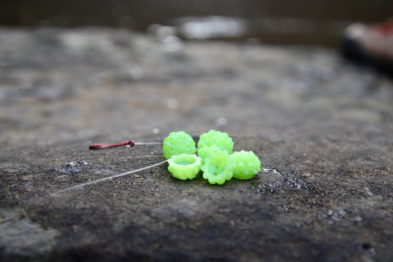 Load image into Gallery viewer, Green Steelhead beads, with a scent chamber siting on a rock