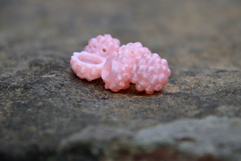 Load image into Gallery viewer, Light Pink Steelhead beads, with a scent chamber siting on a rock
